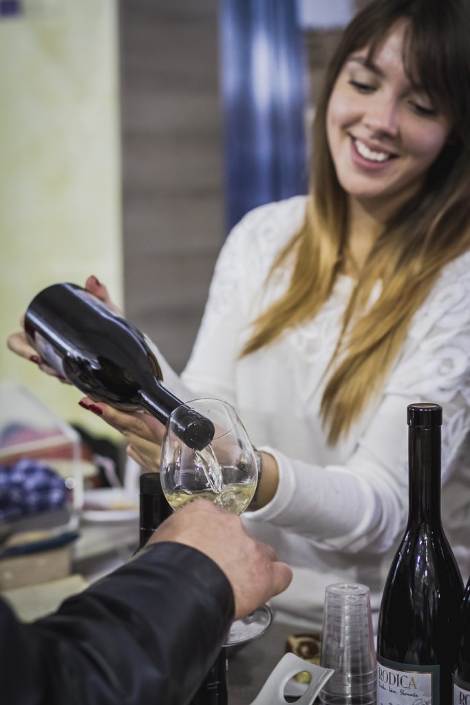 A picture of a girl pouring wine for a guest. Visit wineries with www.krug-travel.com